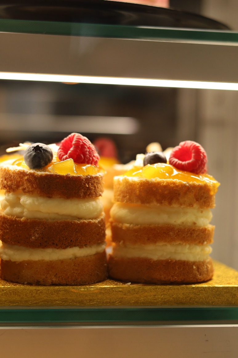 two cakes topped with berries in a display case